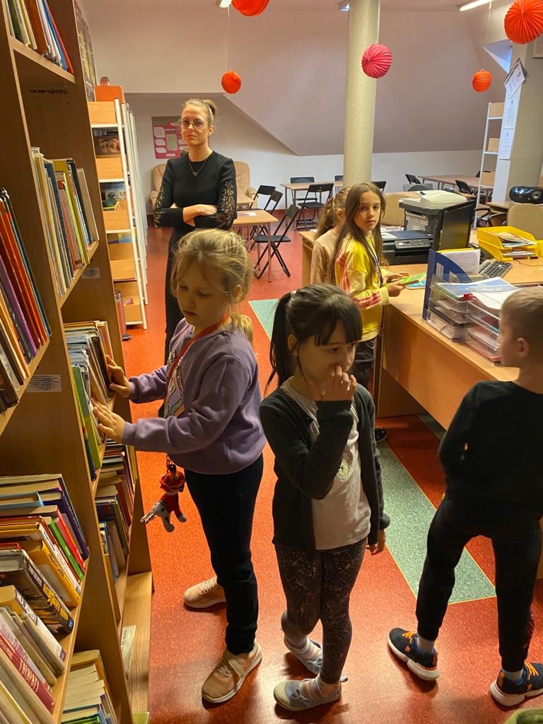 dzieci przeglądają regały z książkami