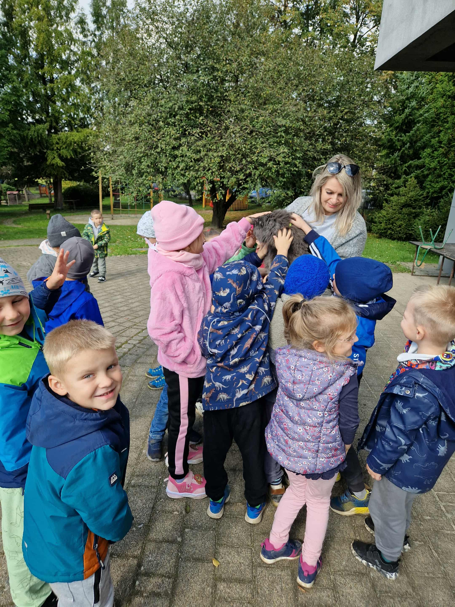 wszytskie dzieci z grupy są na ogrodzie i patrzą na kota