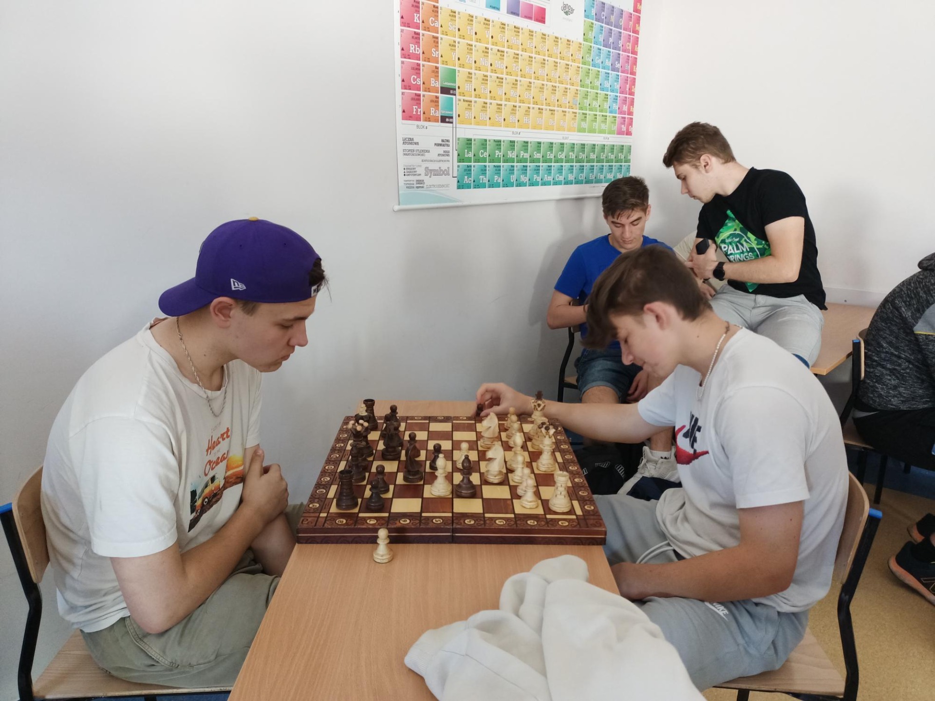 Dwóch uczniów przy szachownicy rozgrywa partię. 
