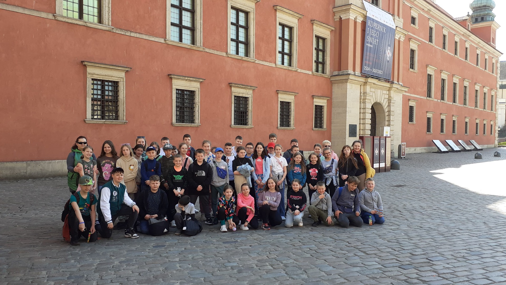 Grupa uczniów wraz z nauczycielami przed Zamkiem Królewskim w Warszawie