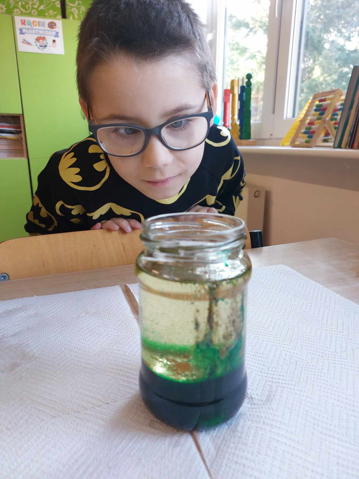 Uczeń obserwuje z bliska jak woda łączy się z olejem i barwnikiem spożywczym
